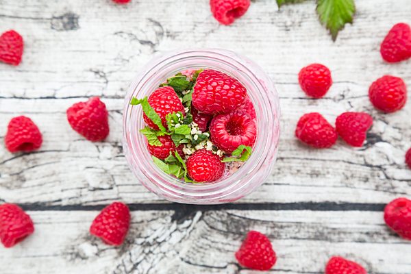 Raspberries, chia, milk, kiwi, hemp seed and mint in a glass