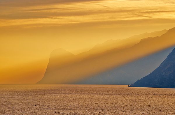 Italy, Torbole, Lake Garda with mountains at sunset