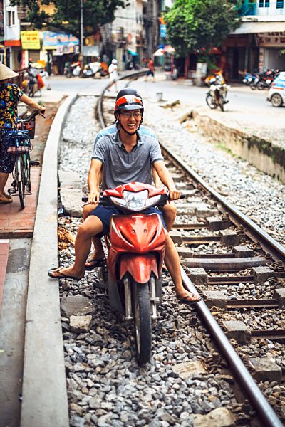 Vietnam, Hanoi, young man with motorbike on railway tracks