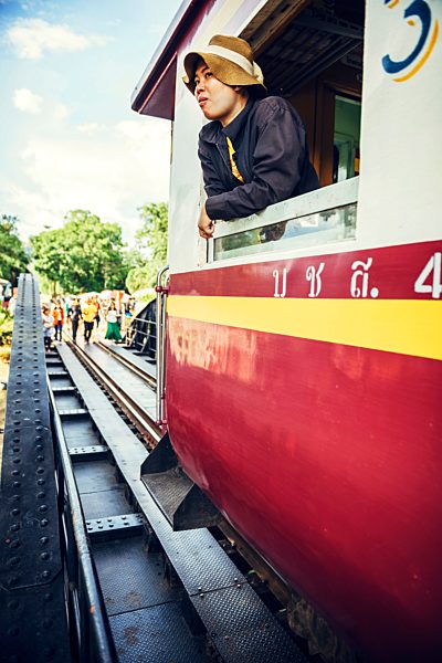 Thailand, Kanchanaburi, woman leaning out of window of a passenger train
