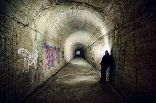 Spain, man leaning on wall of a tunnel