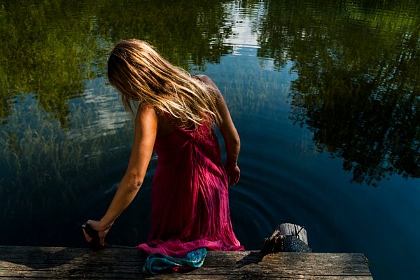 Woman in summer dress getting into lake