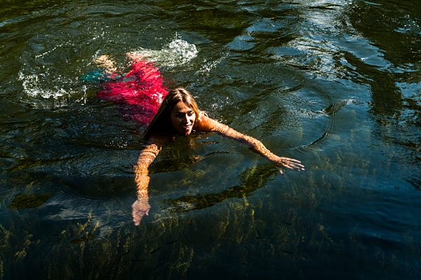 Woman in summer dress swimming in lake