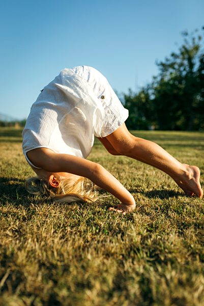 Little girl doing a somersault on a meadow