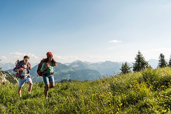 Austria, Tyrol, Tannheimer Tal, young couple hiking on alpine meadow