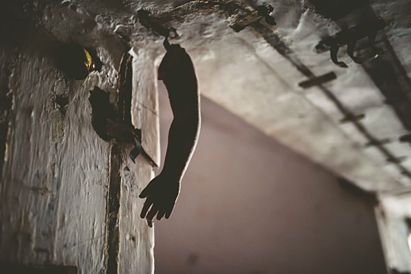 Doll arm hanging from the ceiling of a house in ruins