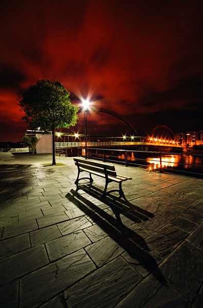 Spain, Galicia, Naron, Promenade with a bench in the foreground at night