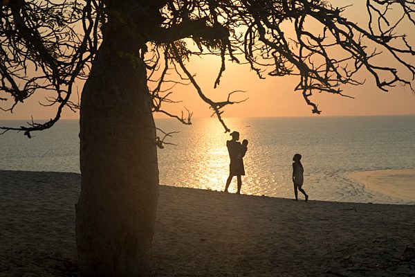 Africa, Madagascar, Woman with children standing at sea at sunset