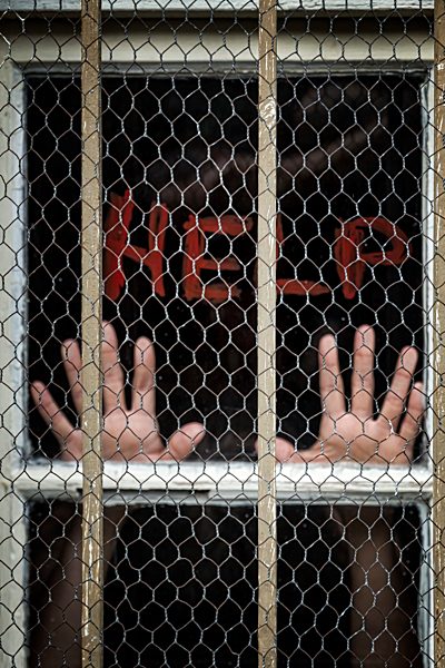 Woman's hand behind metal-grilled window begging for help
