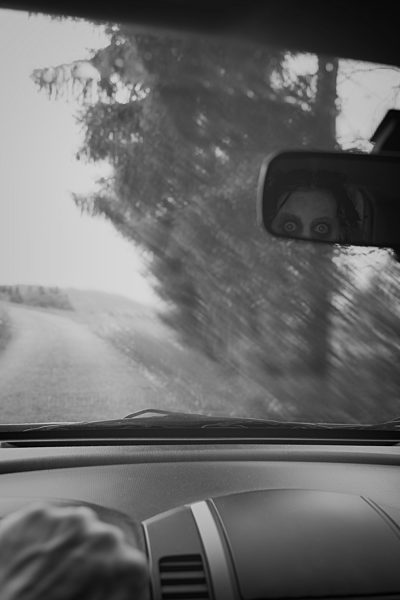 Man driving car while ghost watching him through rear view mirror