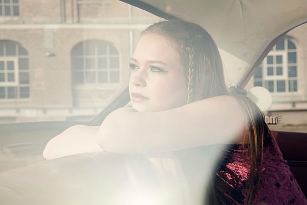 Young woman looking through window of vintage car