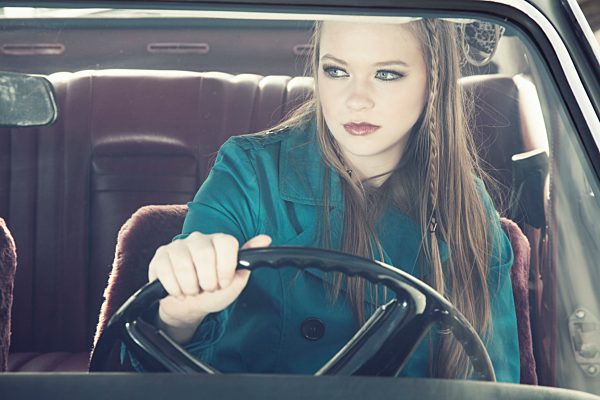 Portrait of young woman at steering wheel of vintage car
