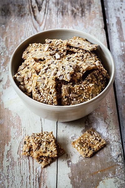 Seed crackers with hemp seeds in bowl, on wood