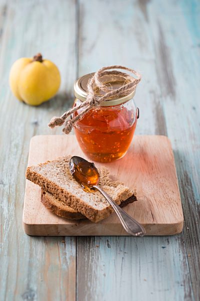 Quince jelly, slice of bread on chopping board