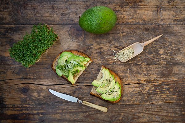Slice of toasted bread with acocado, cress and hemp seeds on wood