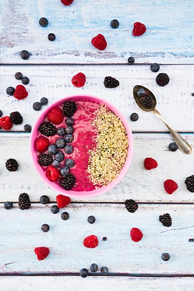 Bowl with fruit smoothie garnished with berries and hemp seeds