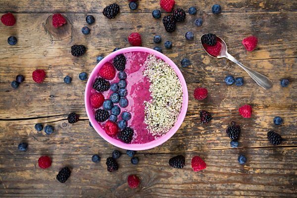Bowl with fruit smoothie garnished with berries and hemp seeds