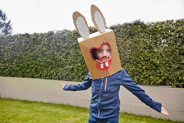 Boy wearing bunny mask in garden