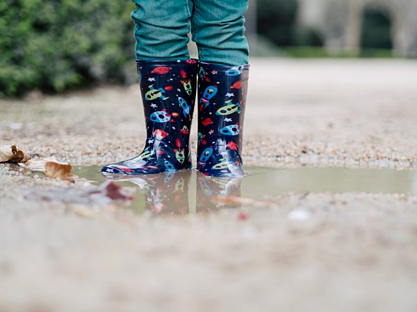 Little boy wearing Wellington boots standing in a puddle, partial view