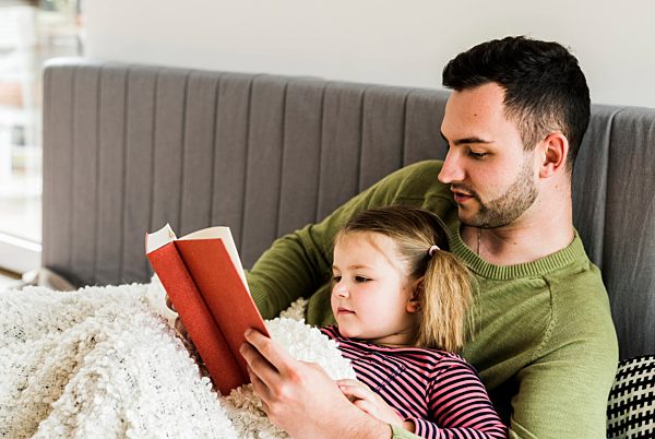 Father and daughter reading a book at home