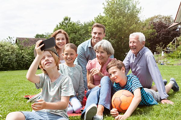 Boy taking selfie of happy extended family in garden