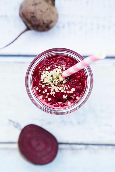 Glass of beetroot smoothie with hemp seed and whole and sliced beetroot