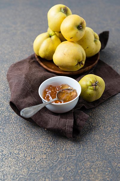 Wooden bowl of quinces and bowl of quince jelly