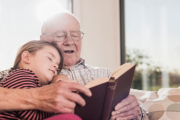 Grandfather reading out story for his granddaughter