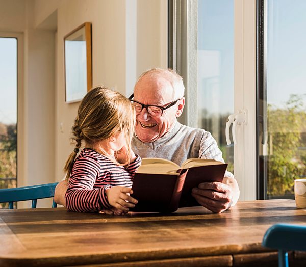 Grandfather reading out story for his granddaughter