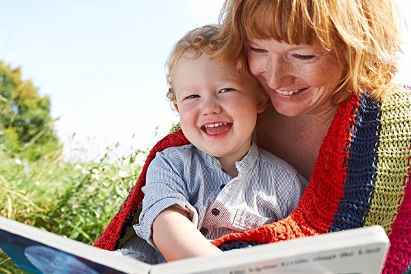 Happy mother and son with picture book in meadow