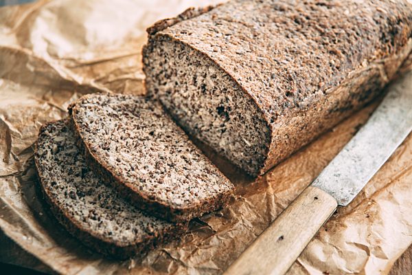 Home-baked wholemeal glutenfree bread and bread knife on brown paper