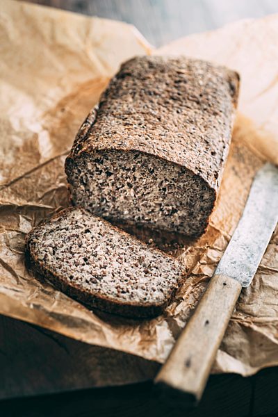 Home-baked wholemeal gluten-ree bread and bread knife on brown paper
