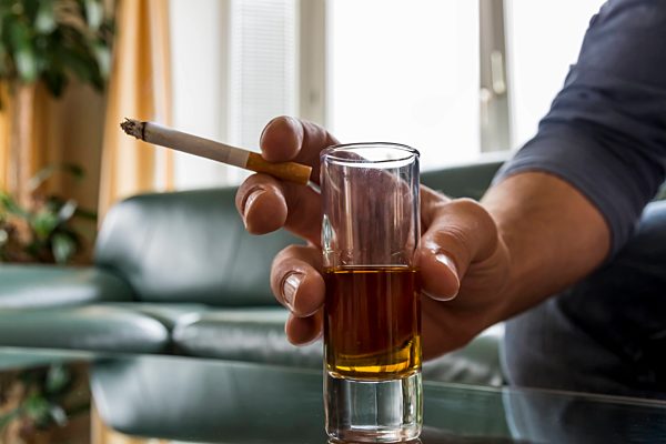 Hand holding cigarette and shot glass