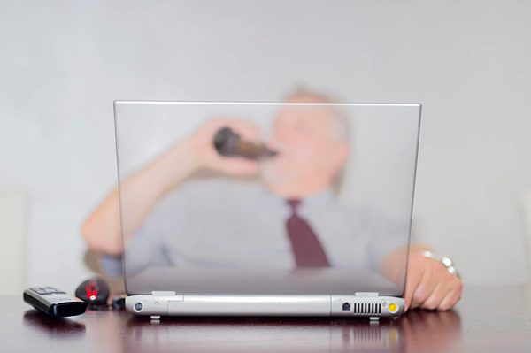 Official drinking beer behind laptop