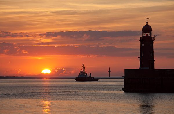 Germany, Bremen, Bremerhaven, Lighthouse on the pier at sunset