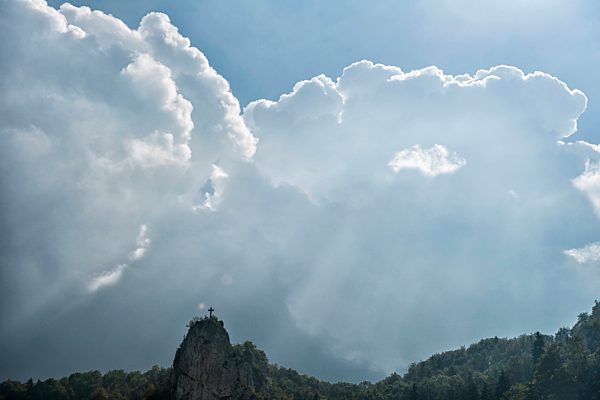 Germany, Baden-Wuerttemberg, Swabian Alps, Danube Valley, Beuron, Petersfelsen with summit cross, dramatic cloudy atmosphere