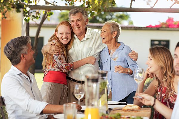 Happy senior couple with family having lunch together outside