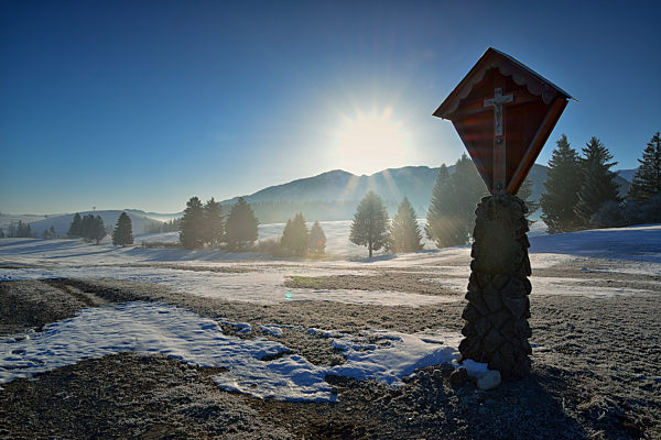 Kreuz in Allgaeuer Landschaft bei Fuessen mit Sonnenaufgang