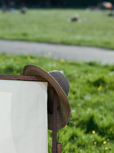A straw hat hanging from the corner of a deck chair