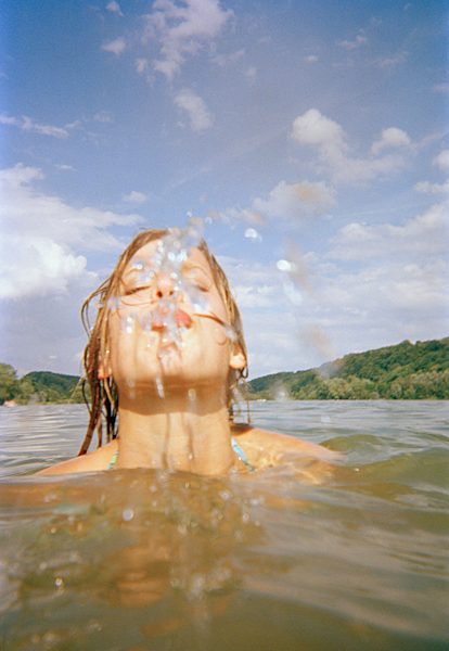A young woman spitting water from a lake