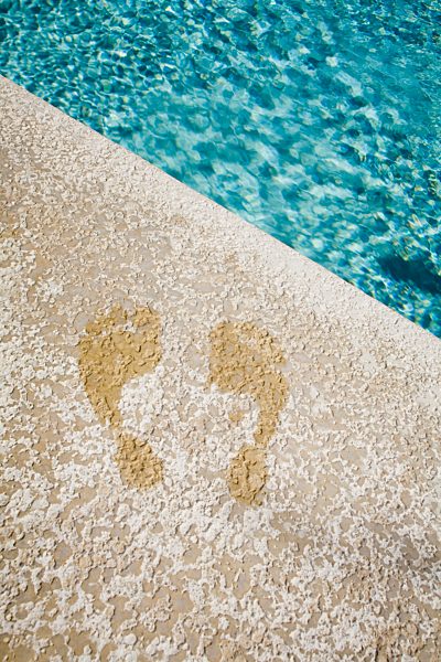 Wet footprints at the edge of a swimming pool