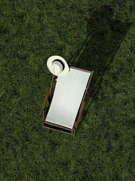 A sun lounger and a sun hat on a grass lawn