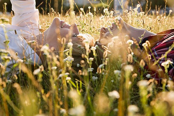 A young couple lying in on their backs in grass, close-up