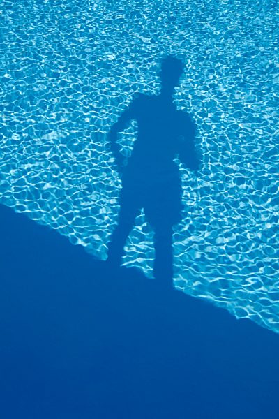 Shadow of a man standing at the edge of a swimming pool