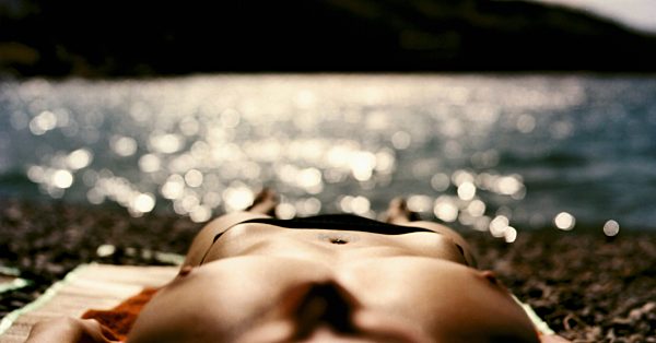 A topless woman sunbathing by a lake