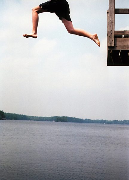 A person jumping off a platform into a lake