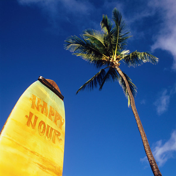 A surfboard with Happy Hour on it and a palm tree
