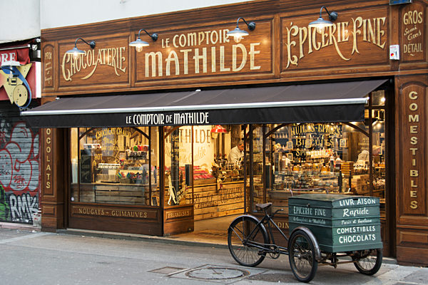 The Richly Decorated Facade Of A Traditional Chocolate Store With Antique Delivery Cart In Front; Paris, France