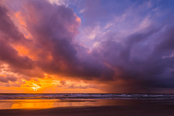 Offshore rain falls over the Atlantic Ocean at sunrise. Digitally altered by removing a silhouetted person from foreground; Cocoa Beach, Florida, United States of America