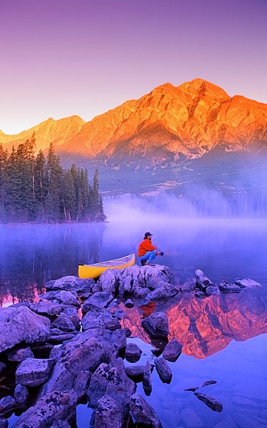 Man sitting on rock with mountains in background